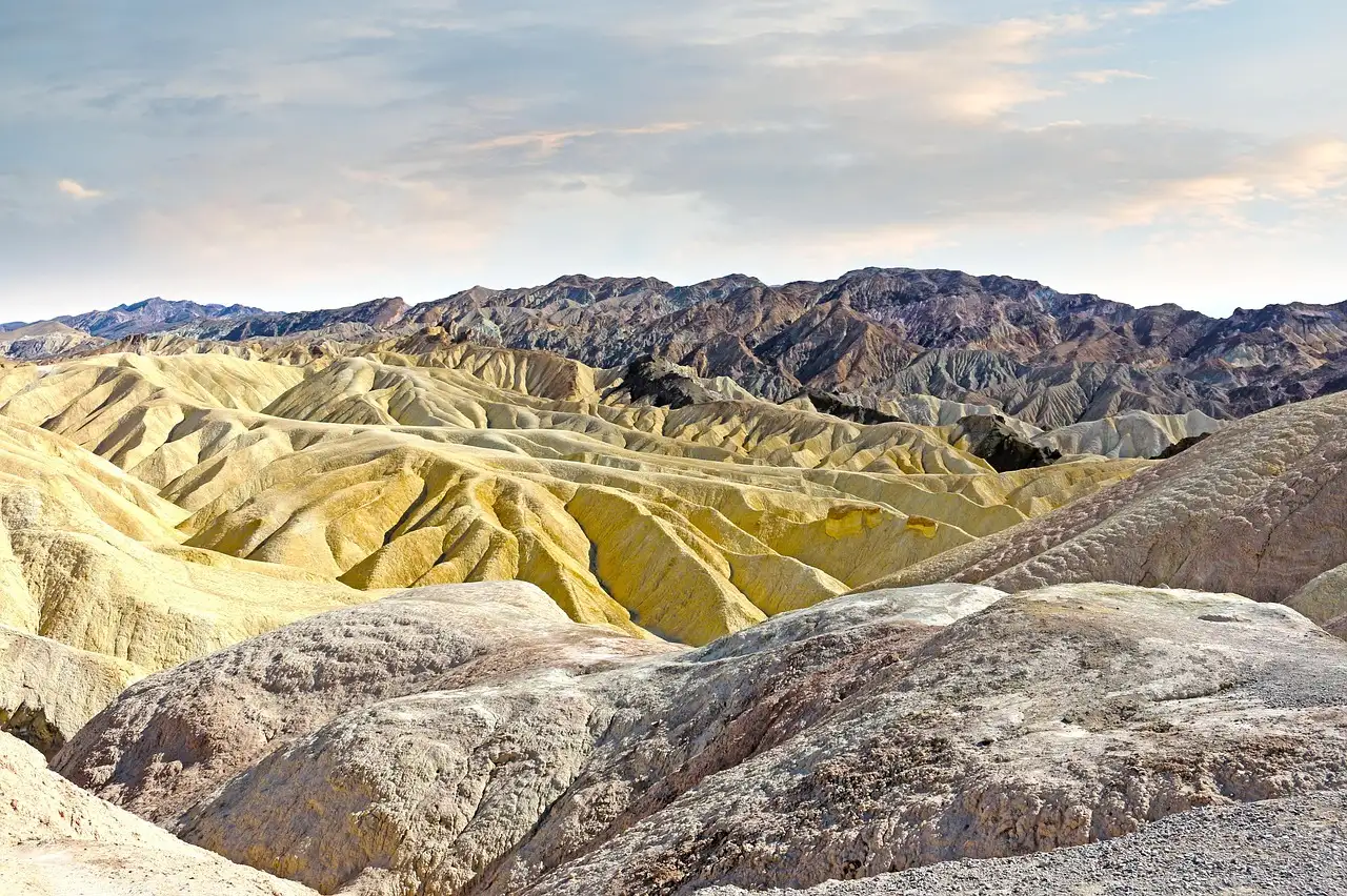 Rolling yellow and brown badlands in Death Valley below jagged mountains