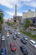Cars driving along Las Vegas Boulevard on the Strip, with the Paris tower in the distance