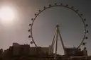 The High Roller observation wheel in full, its cabins ringing the rim, against a hazy sunny sky