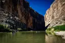 Small kayaks on a calm river between tall desert canyon walls