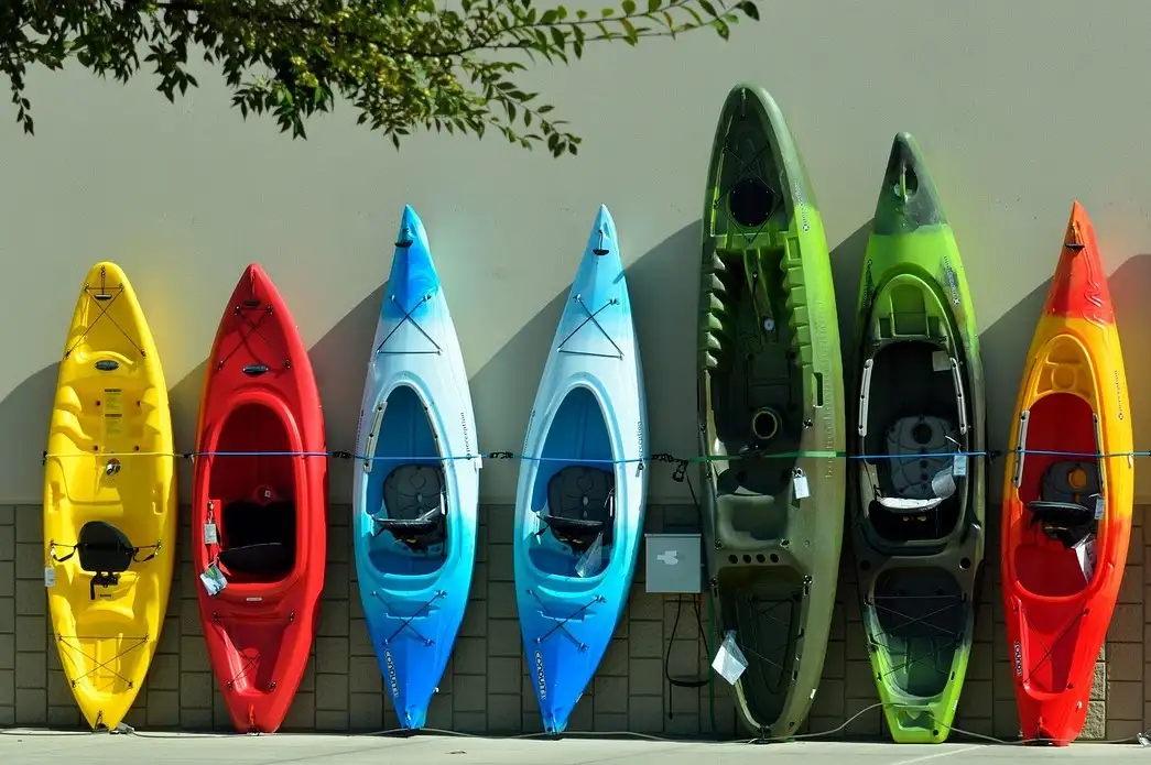 A row of colorful kayaks standing upright against a wall