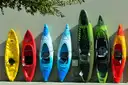 A row of colorful kayaks standing upright against a wall