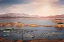 A marina full of boats on Lake Mead below desert mountains at sunset
