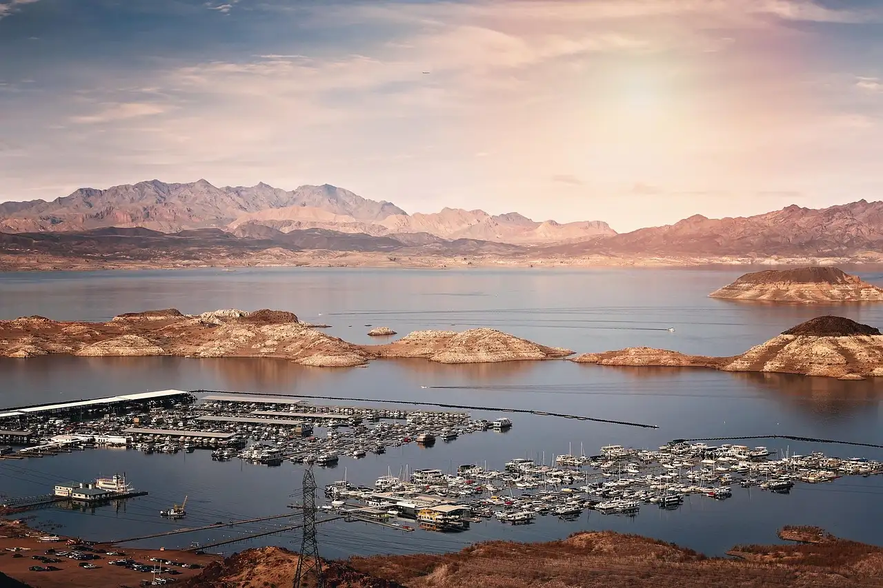 A marina full of boats on Lake Mead below desert mountains at sunset