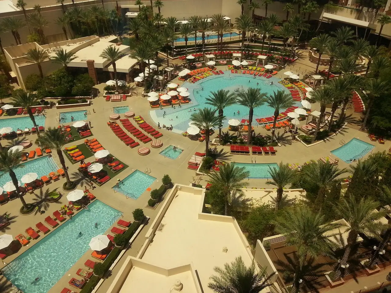 A Las Vegas resort pool deck from above, with several pools, palms and sun loungers
