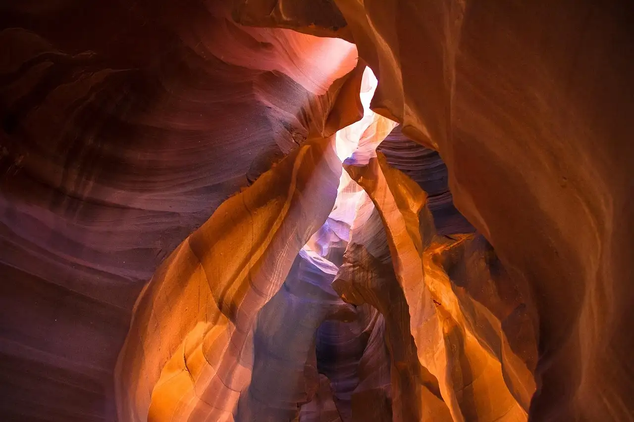 Orange and purple sandstone walls with light falling into Antelope Canyon