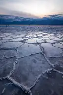 Cracked salt flats at Badwater Basin in Death Valley at dusk, with mountains behind
