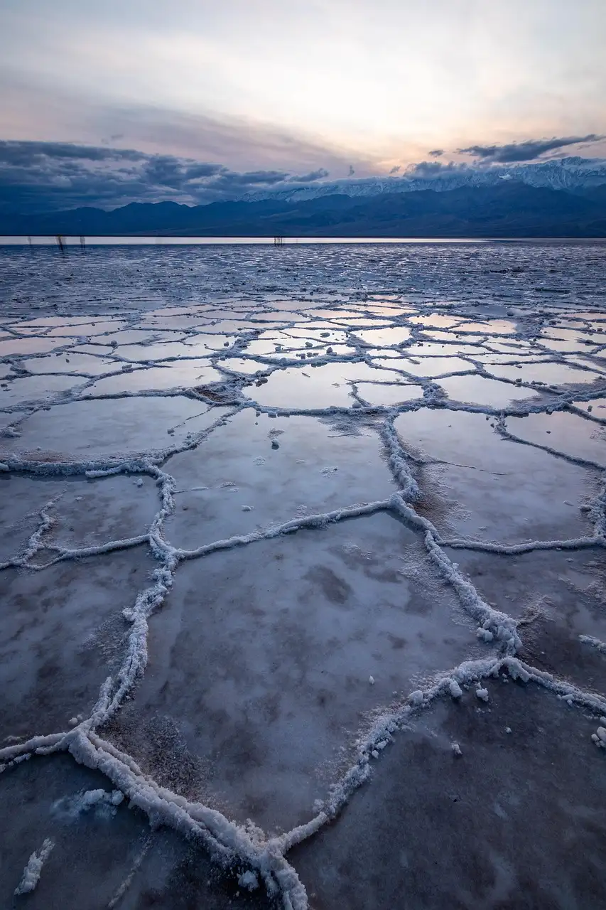 Cracked salt flats at Badwater Basin in Death Valley at dusk, with mountains behind