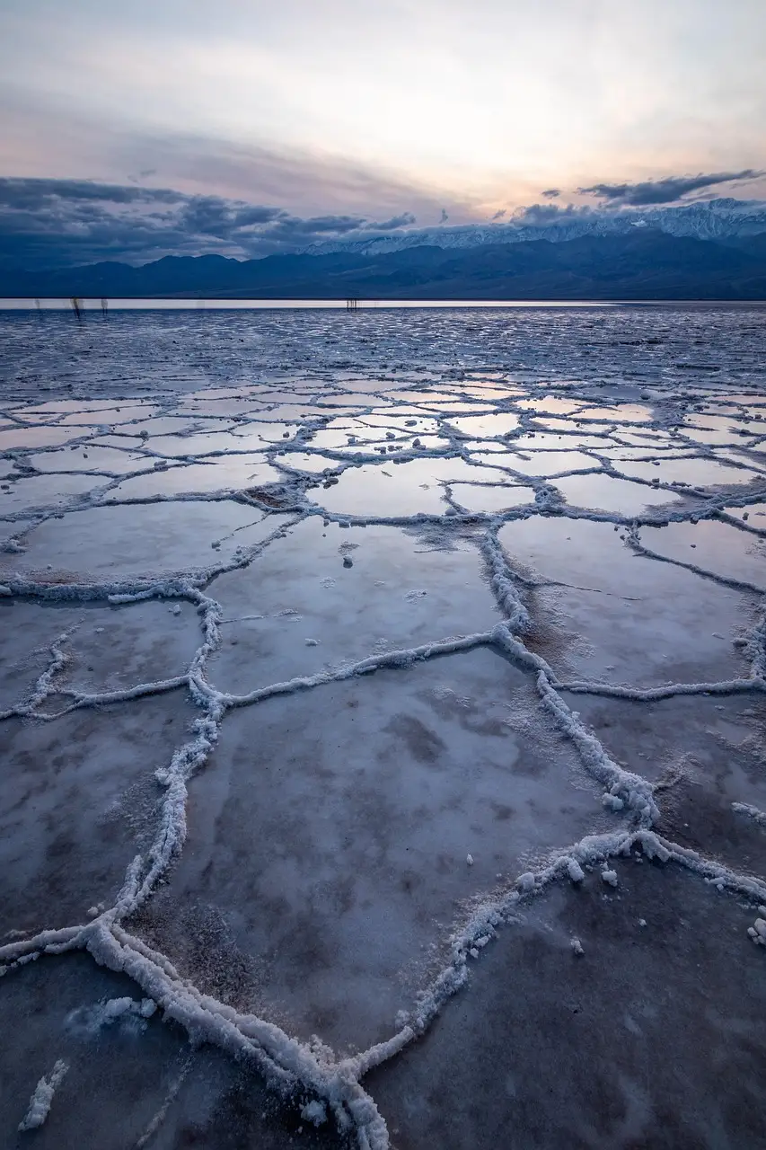 Cracked salt flats at Badwater Basin in Death Valley at dusk, with mountains behind