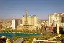 The Las Vegas Strip in hazy afternoon sun, with the Bellagio lake in front and dry mountains behind