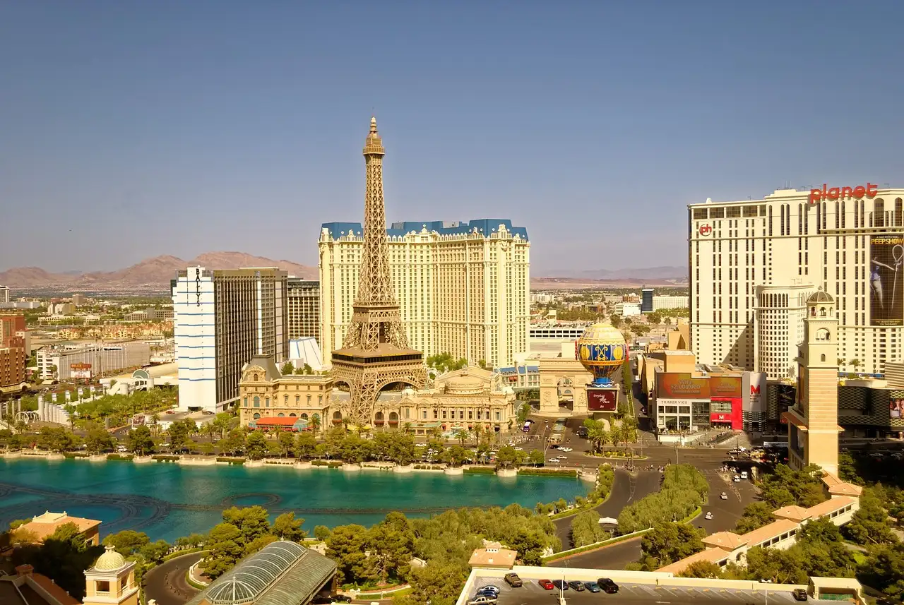 The Las Vegas Strip in hazy afternoon sun, with the Bellagio lake in front and dry mountains behind