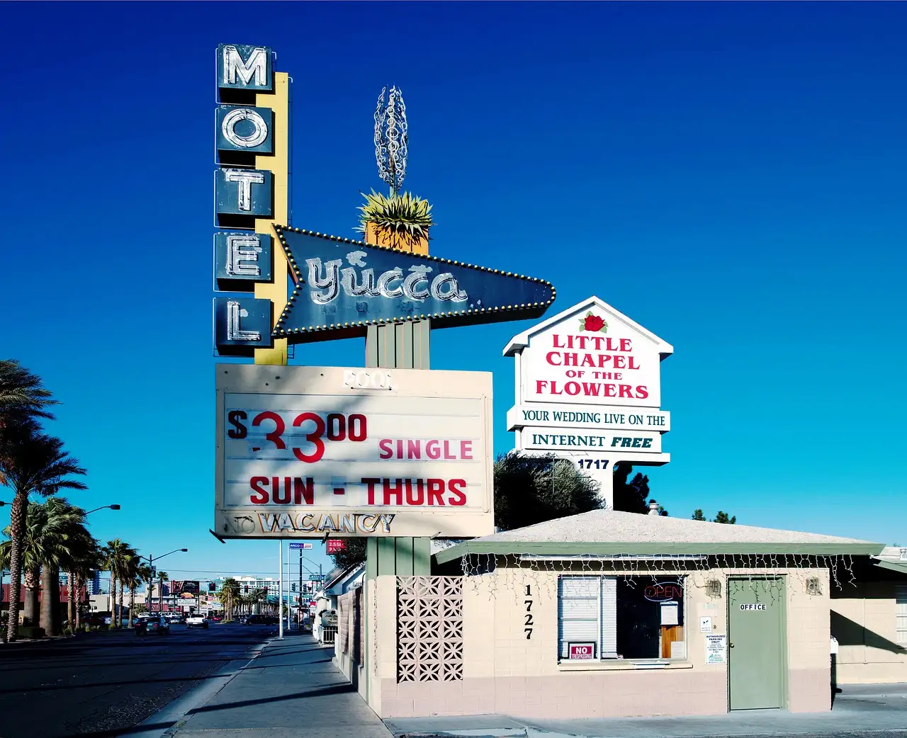 A Las Vegas wedding chapel sign beside a motel sign on a sunny street