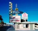 A Las Vegas wedding chapel sign beside a motel sign on a sunny street