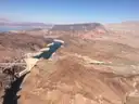Air view of desert mountains with a lake, a dam and an arched bridge in the canyon