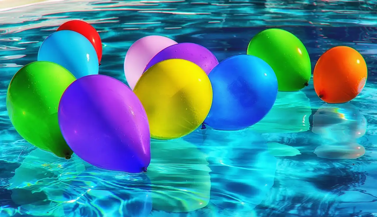Colorful balloons floating on bright blue pool water