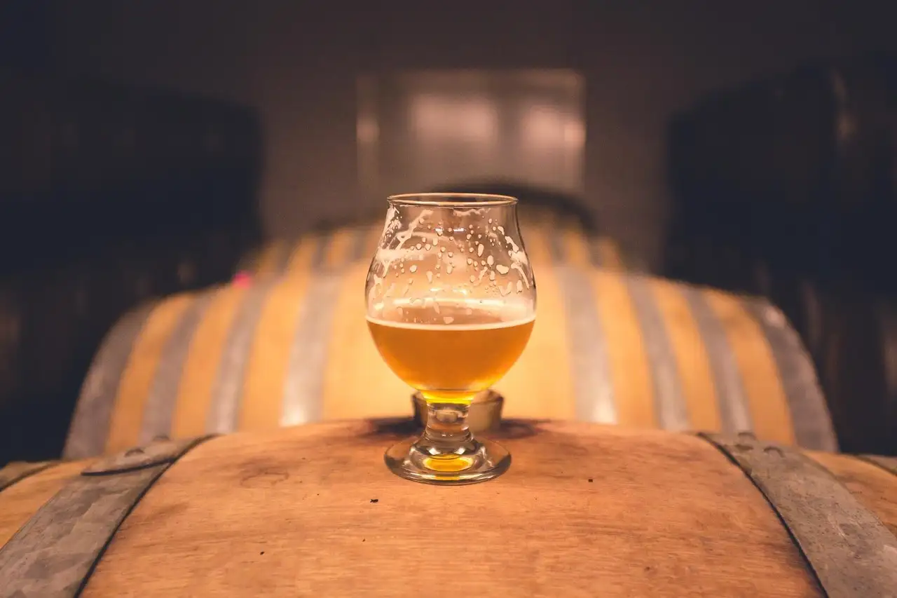 Glass of pale beer standing on a wooden barrel