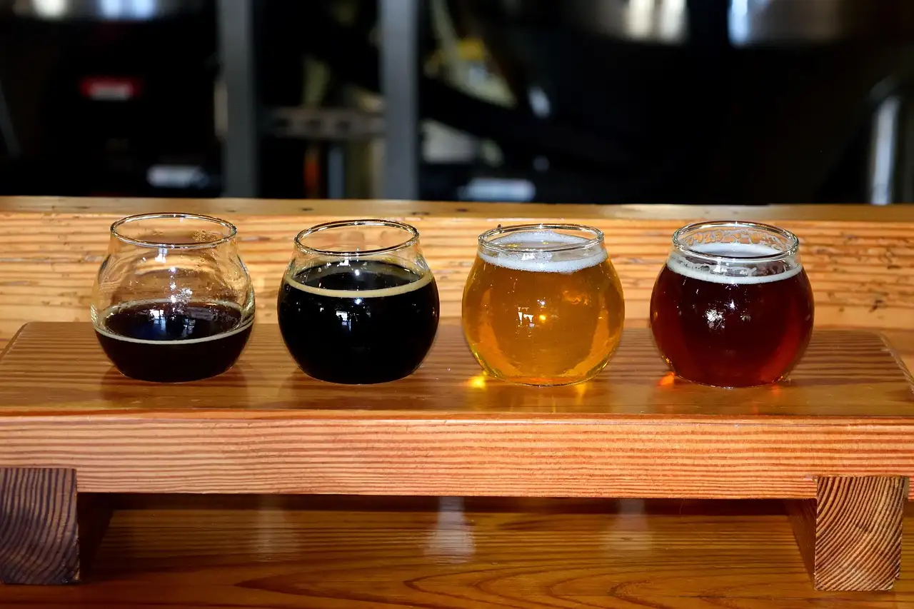 Four tasting glasses of craft beer on a wooden board