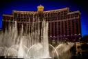 Bellagio fountain jets in front of the lit hotel at dusk