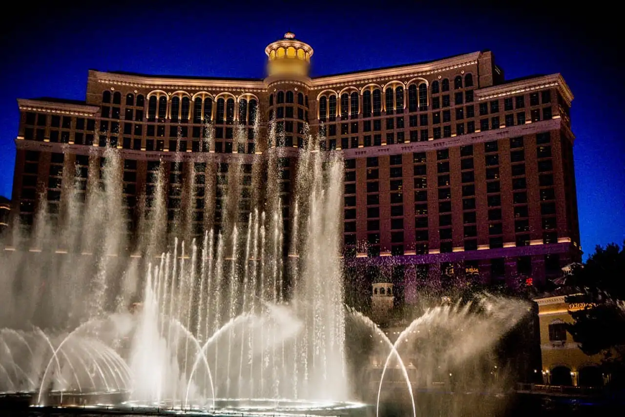 Bellagio fountain jets in front of the lit hotel at dusk