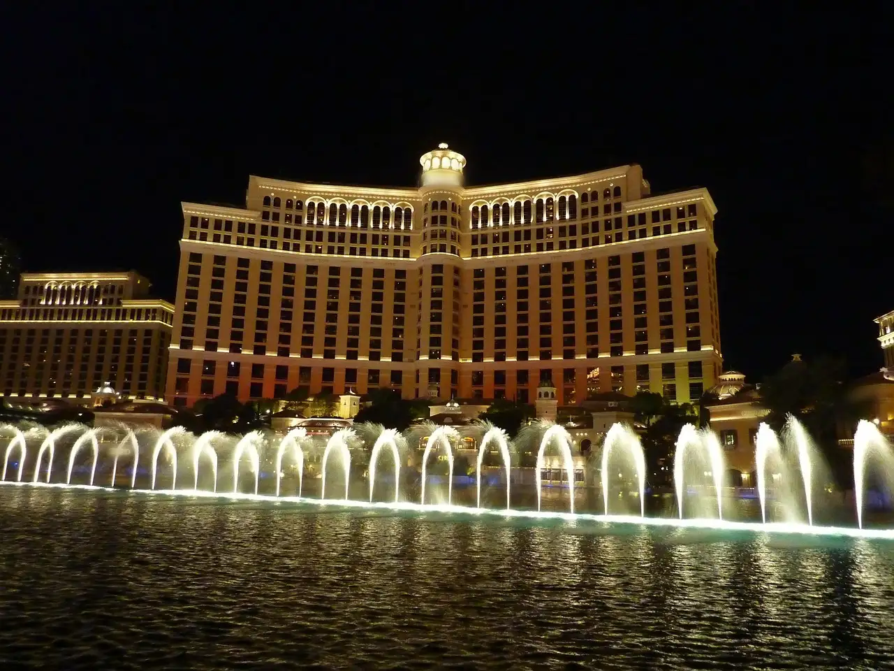 A row of lit Bellagio fountain jets in front of the hotel at night