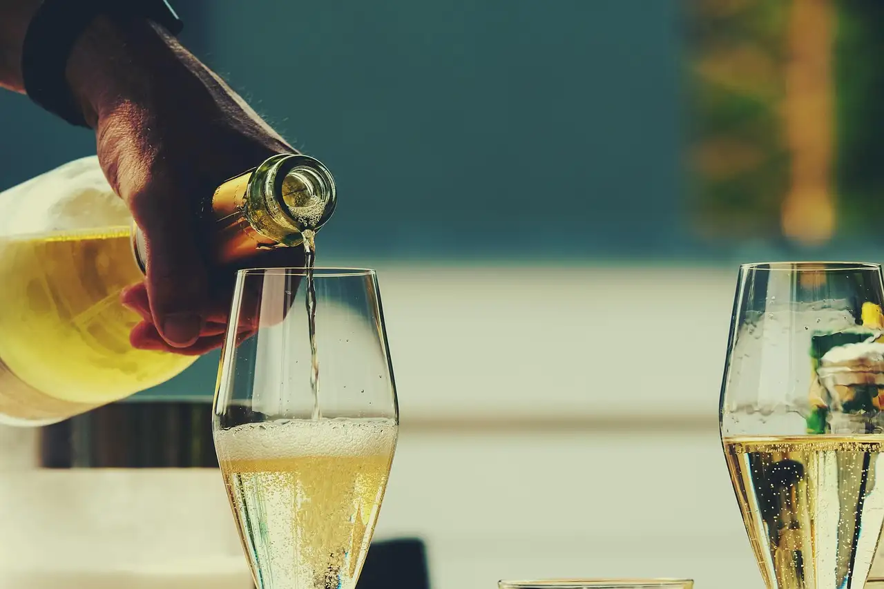 Sparkling wine being poured into a tall glass next to a second full glass