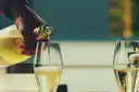 Sparkling wine being poured into a tall glass next to a second full glass