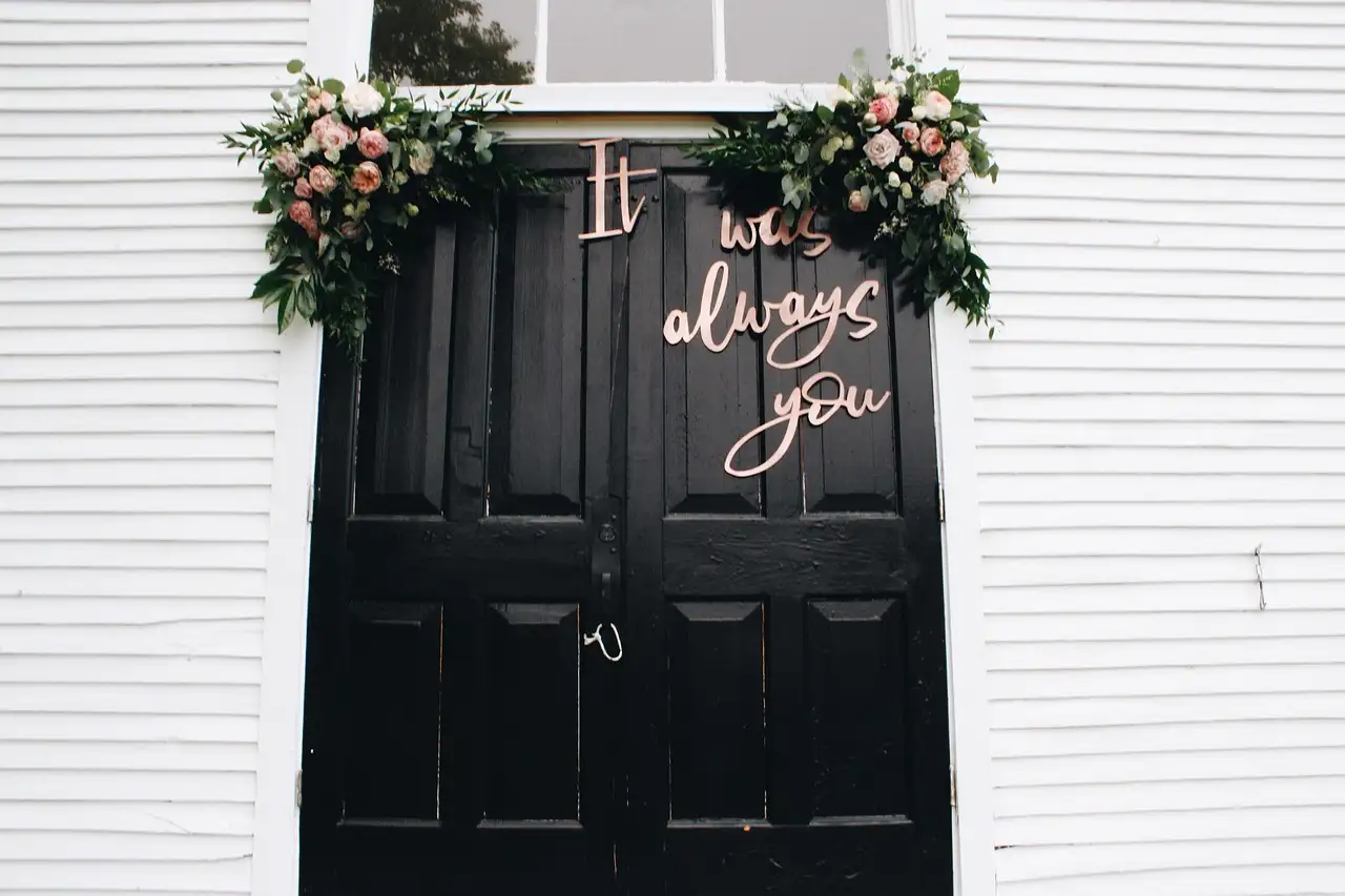 Black chapel doors framed with roses and the words It was always you