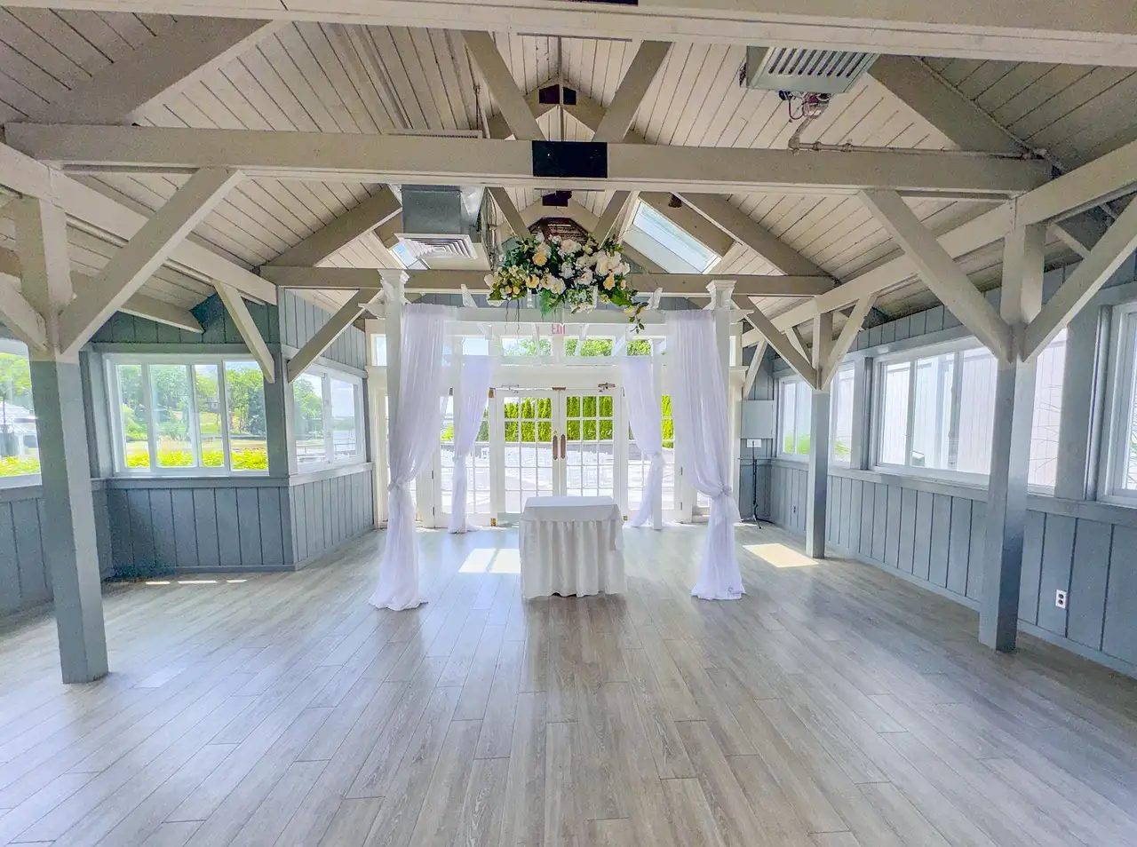 Empty white wedding chapel with wooden beams, a draped arch and flowers