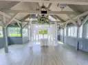 Empty white wedding chapel with wooden beams, a draped arch and flowers