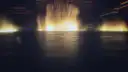Dancing fountain jets lit gold over a dark lake in front of a resort hotel at night