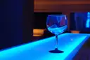 Empty glass on a glowing blue bar counter in a dim lounge