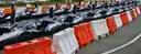 Rows of empty go-karts lined up behind orange and white barriers at an open-air track