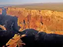 Sunlit orange canyon cliffs seen from the air above a deep shadowed gorge