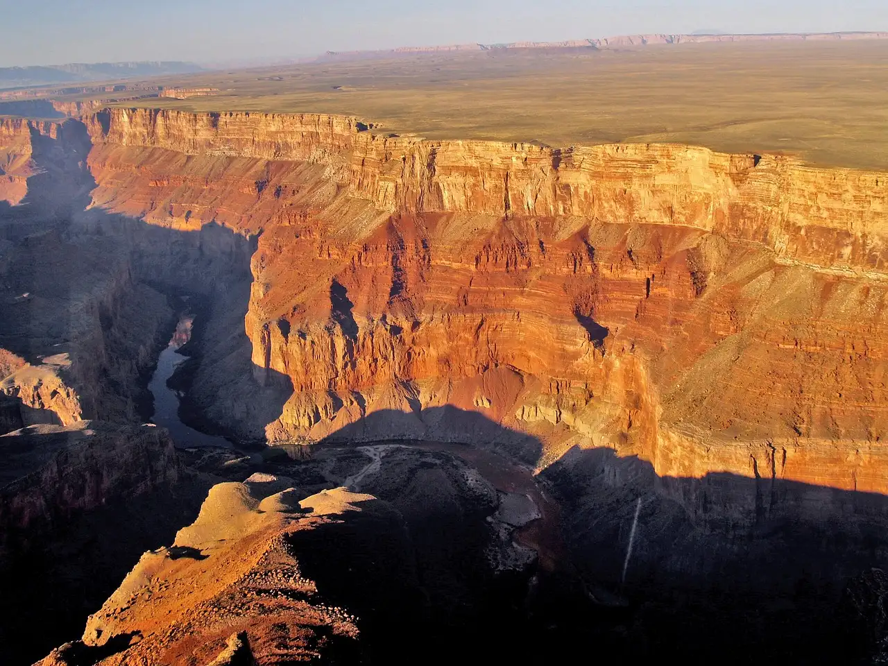 Sunlit orange canyon cliffs seen from the air above a deep shadowed gorge