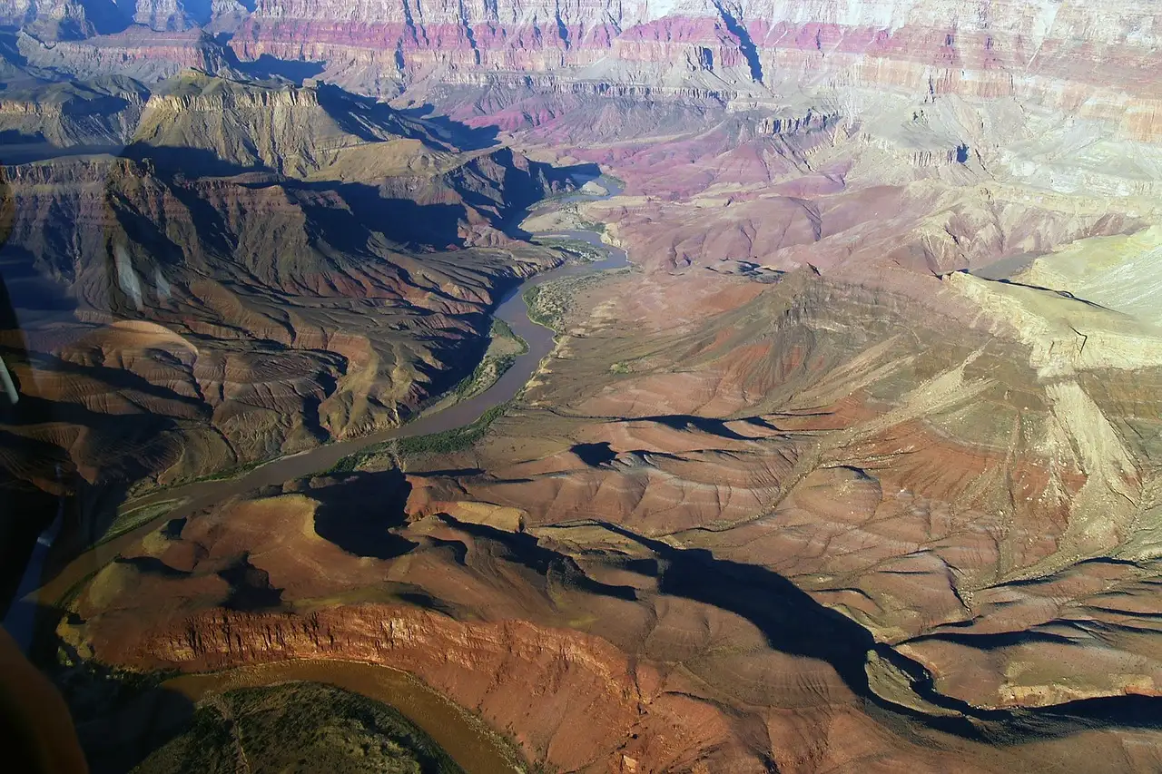 Air view down into a deep canyon with a river between layered slopes