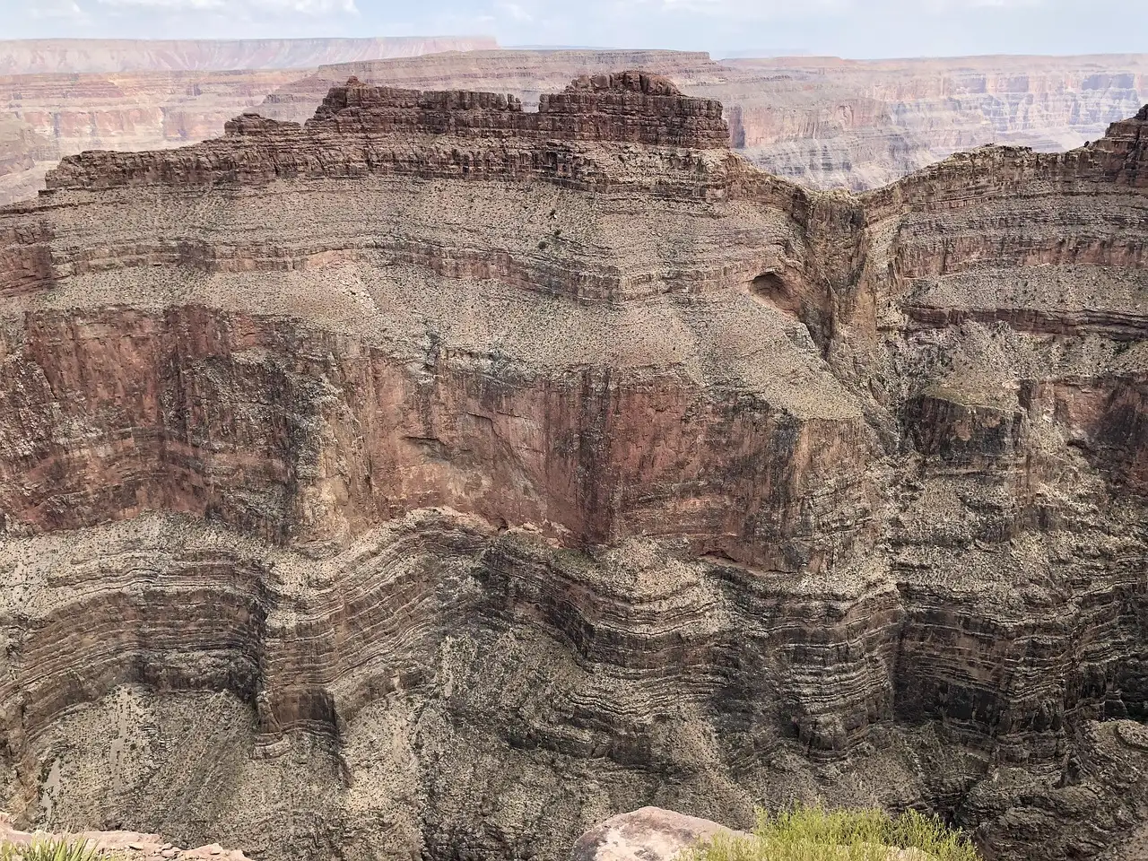 Tall canyon wall banded in red, brown and grey rock