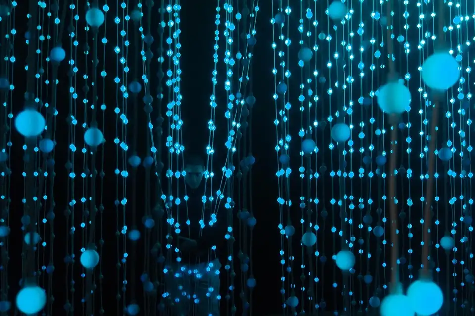 Strings of blue lights hanging in a dark room, a light installation