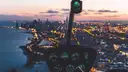 View from a helicopter cockpit over a lakeside city glittering with lights at dusk