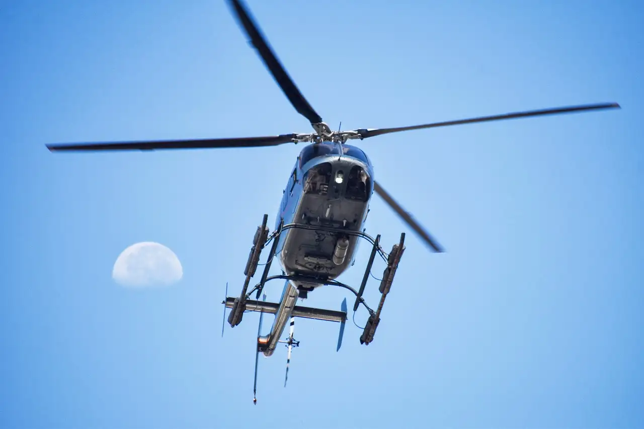 Helicopter seen from below against a blue sky with the moon