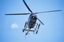 Helicopter seen from below against a blue sky with the moon