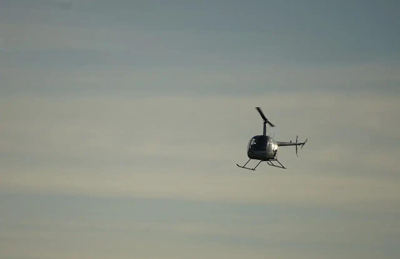 Small helicopter flying in a grey evening sky