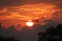 Red and white helicopter flying past the setting sun