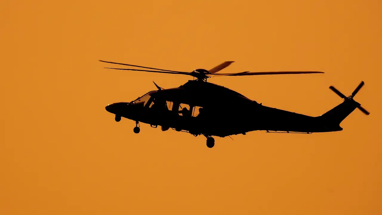 Helicopter in black silhouette against an orange sky