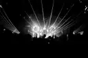 Laser beams fanning over a stage above a crowd in silhouette, black and white