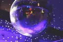 Large mirror ball in purple light throwing light dots on a wall