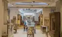 Long museum hall with glass display cases and stone statues, a few visitors in the distance