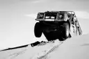 Off-road truck climbing over a sand dune, black and white
