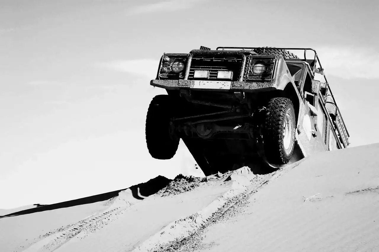 Off-road truck climbing over a sand dune, black and white