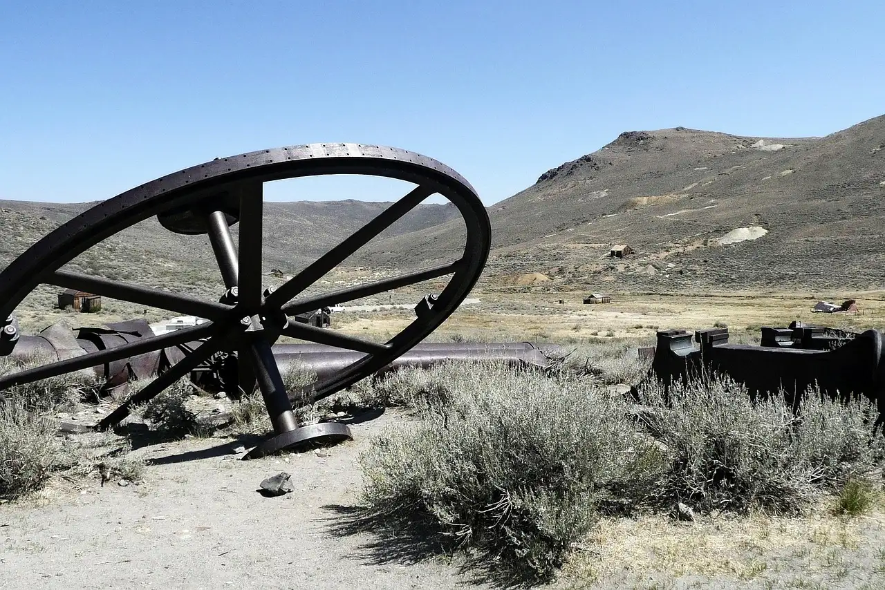 Rusted iron mine wheel lying in sagebrush on a dry hillside
