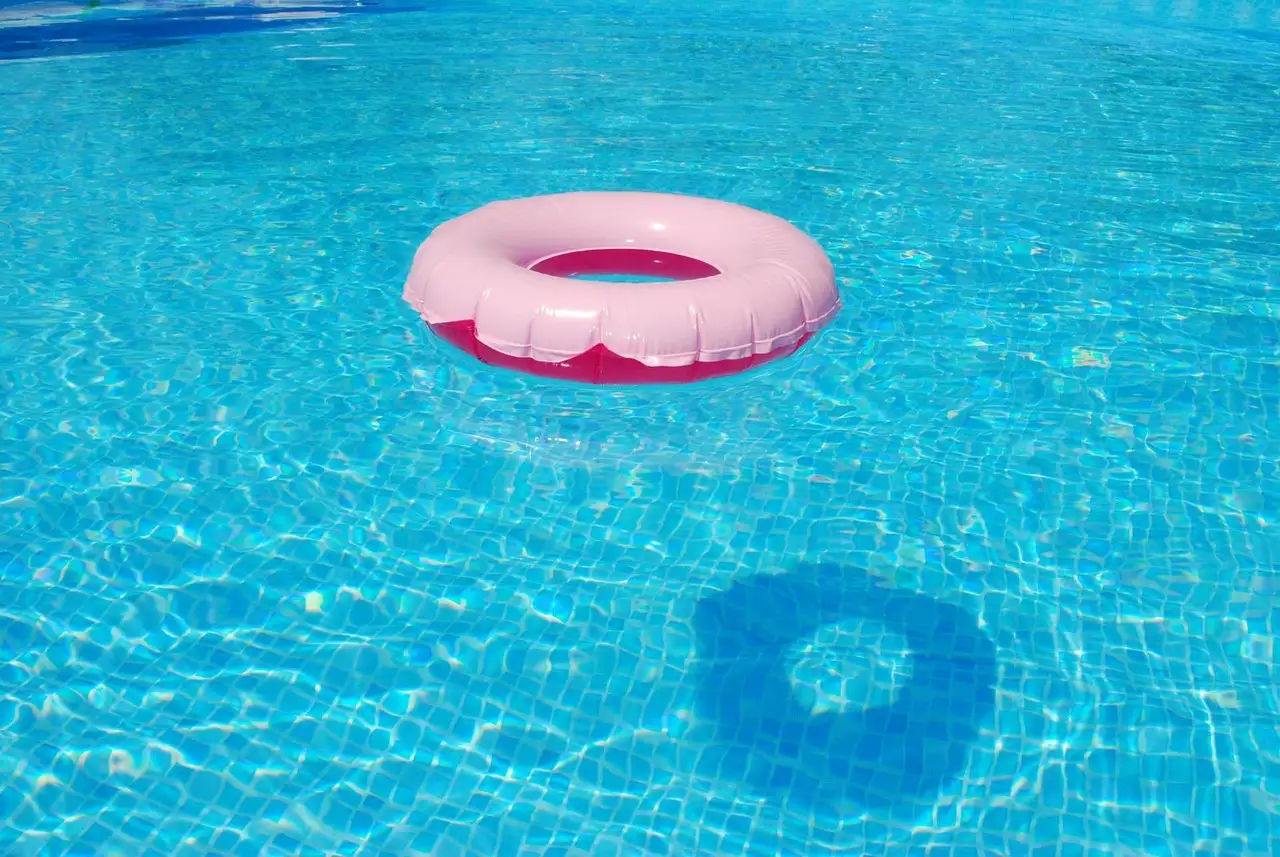 Pink swim ring floating on clear blue pool water